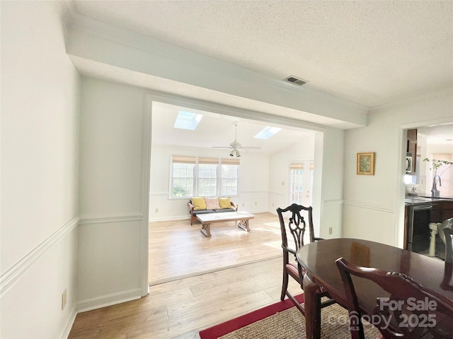 944 Evian Ln, Matthews, NC 28015 - dining area featuring a skylight, light wood-type flooring, a textured ceiling, a ceiling fan, and ornamental molding
