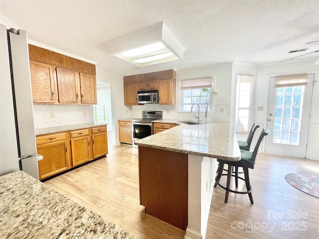 944 Evian Ln, Matthews, NC 28015 - kitchen featuring appliances with stainless steel finishes, a sink, a peninsula, light wood-style flooring, and a kitchen bar