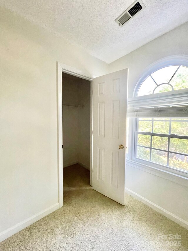 944 Evian Ln, Matthews, NC 28015 - unfurnished bedroom with light colored carpet, a textured ceiling, baseboards, and a walk in closet