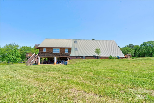 rear view of property featuring a wooden deck, stairs, a yard, and metal roof