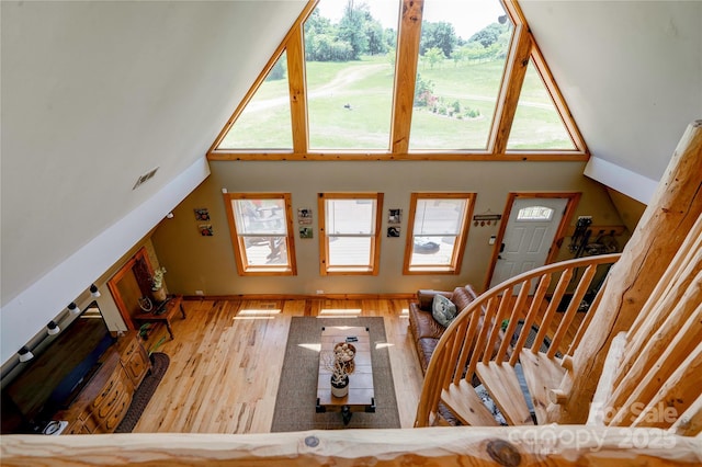 living area featuring a towering ceiling, a wealth of natural light, and wood finished floors