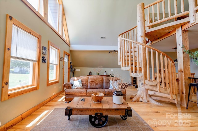 living room with stairway, a high ceiling, wood finished floors, and visible vents