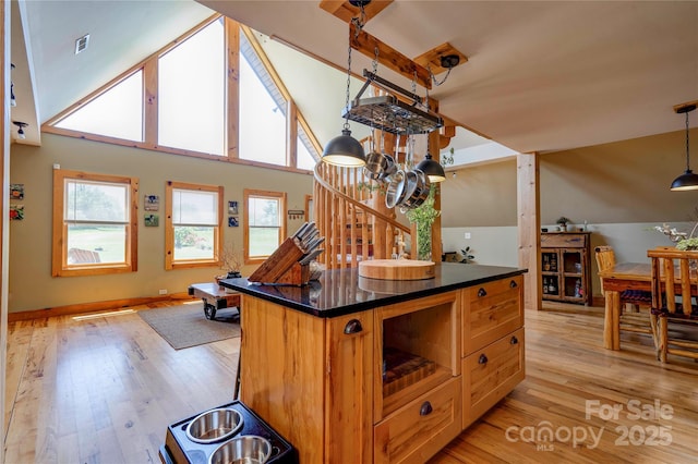 kitchen featuring a kitchen island, visible vents, pendant lighting, dark countertops, and light wood-style floors