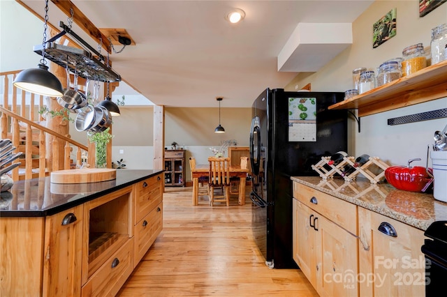 kitchen with light brown cabinetry, open shelves, hanging light fixtures, light wood-style floors, and freestanding refrigerator