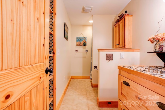 corridor featuring baseboards, light tile patterned flooring, and visible vents