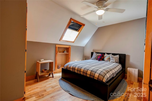 bedroom with ceiling fan, light wood finished floors, and lofted ceiling with skylight