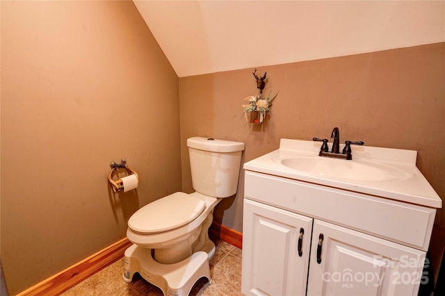 bathroom featuring vanity, baseboards, vaulted ceiling, and toilet