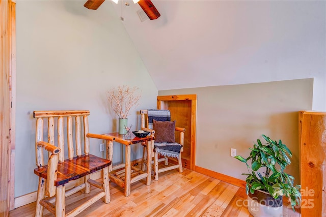 living area featuring a ceiling fan, baseboards, vaulted ceiling, and wood finished floors
