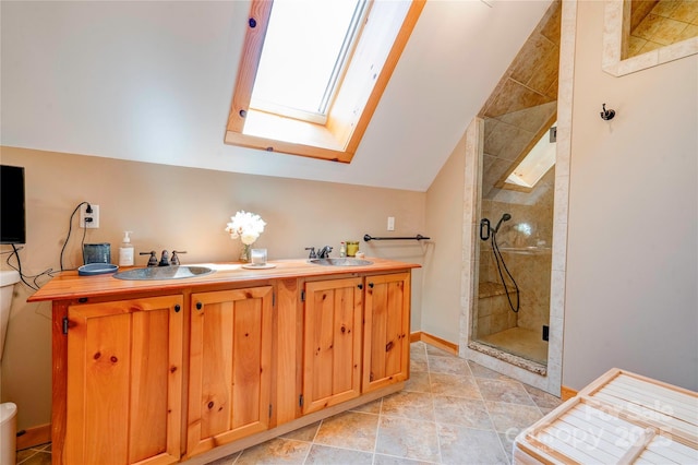 full bathroom featuring double vanity, a tile shower, a sink, and lofted ceiling with skylight