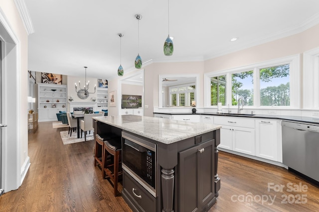 kitchen featuring dark wood-style flooring, a sink, a notable chandelier, ornamental molding, and stainless steel appliances