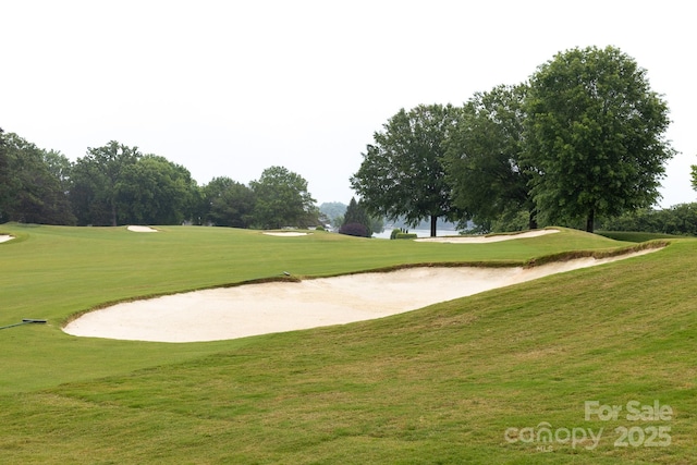 surrounding community with golf course view and a yard
