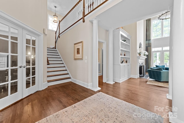entrance foyer with a high ceiling, a fireplace, french doors, and wood finished floors