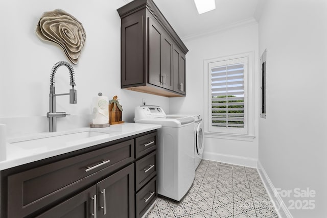 clothes washing area with crown molding, baseboards, a sink, cabinet space, and independent washer and dryer