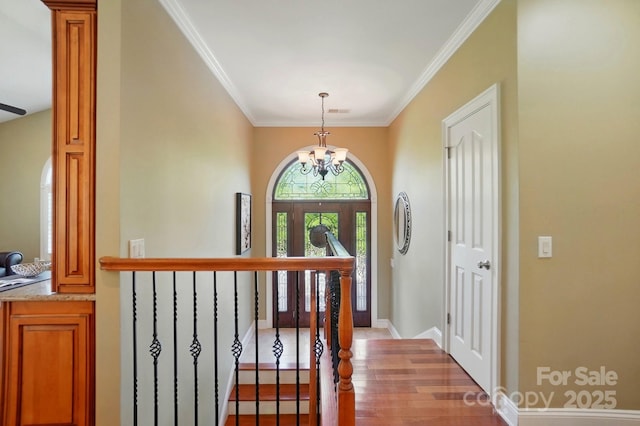 entryway with an inviting chandelier, ornamental molding, baseboards, and wood finished floors