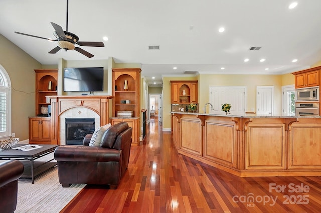 living room featuring visible vents, ceiling fan, wood finished floors, and a fireplace