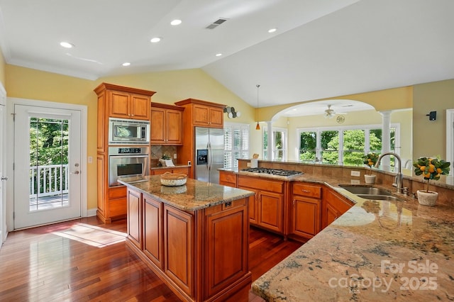 kitchen featuring built in appliances, a kitchen island, dark wood-style floors, ornate columns, and a sink