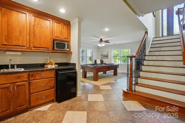 kitchen with billiards, brown cabinets, dishwasher, a sink, and stainless steel microwave