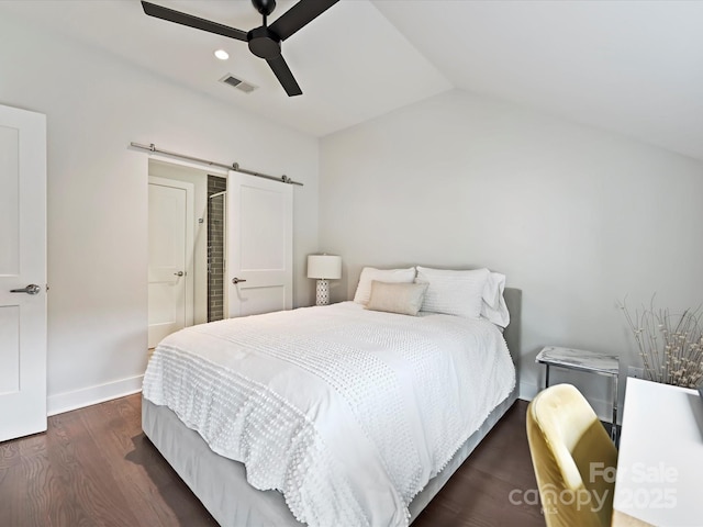 bedroom with visible vents, wood finished floors, a barn door, baseboards, and lofted ceiling