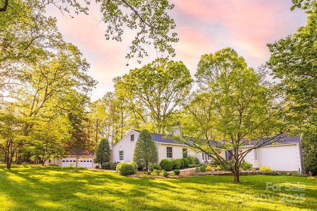 property exterior at dusk with a lawn and a garage