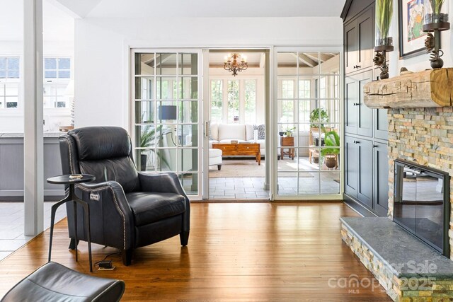 living area with wood-type flooring, a notable chandelier, and a fireplace