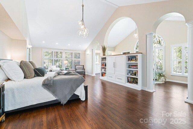 bedroom with arched walkways, multiple windows, ornate columns, and dark wood-type flooring