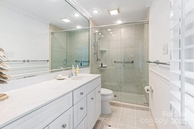 bathroom featuring crown molding, tile patterned flooring, a stall shower, and toilet