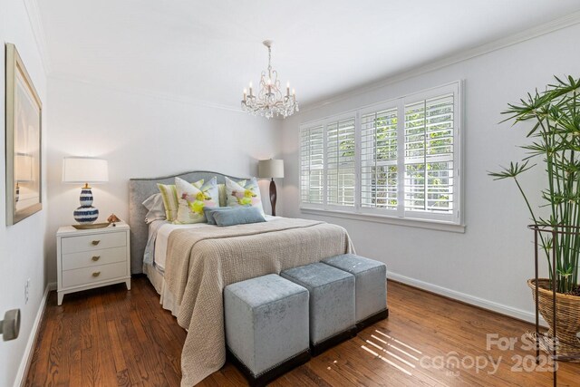 bedroom featuring baseboards, crown molding, wood finished floors, and an inviting chandelier