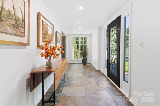 doorway to outside featuring baseboards, recessed lighting, and stone finish flooring