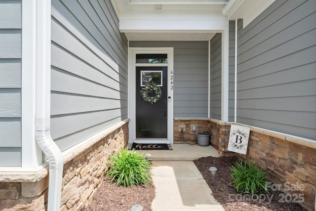 entrance to property featuring a porch and stone siding