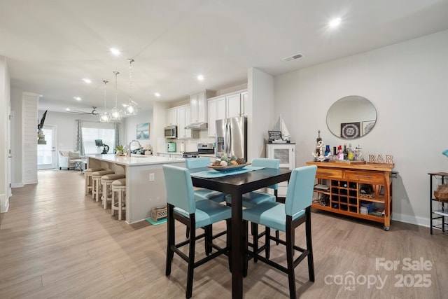 dining room featuring visible vents, light wood-style flooring, and baseboards