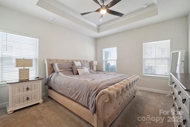 bedroom featuring ceiling fan, light carpet, baseboards, a tray ceiling, and visible vents