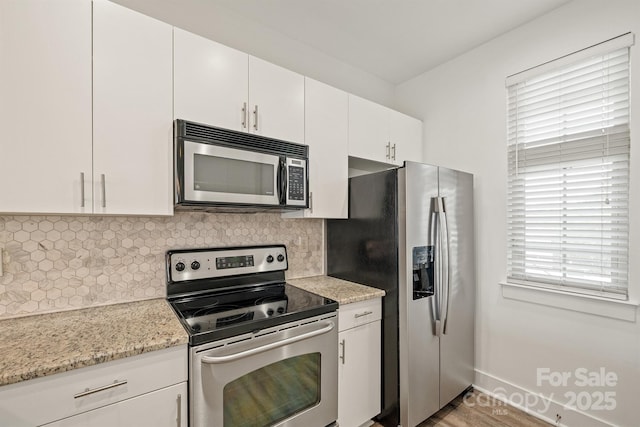 1101 W 1st St Unit 408, Charlotte, NC 28202 - kitchen featuring appliances with stainless steel finishes, backsplash, white cabinets, and light stone counters