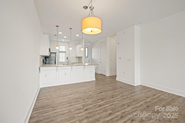 1101 W 1st St Unit 408, Charlotte, NC 28202 - kitchen with a peninsula, light wood finished floors, white cabinets, a sink, and recessed lighting