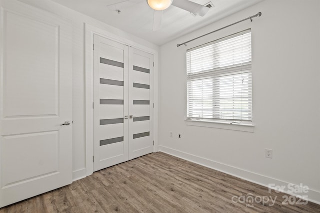 1101 W 1st St Unit 408, Charlotte, NC 28202 - unfurnished bedroom with wood finished floors, multiple windows, baseboards, and a ceiling fan
