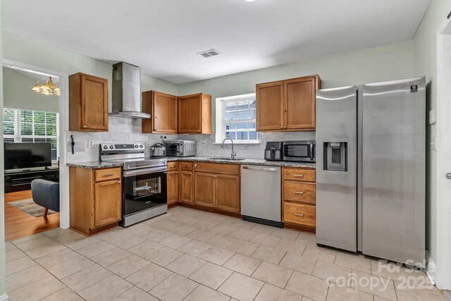 kitchen featuring wall chimney range hood, appliances with stainless steel finishes, tasteful backsplash, and plenty of natural light