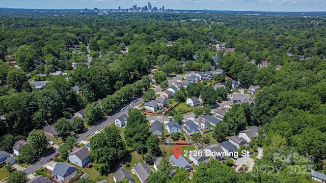 aerial view of property's location featuring a forest and nearby suburban area