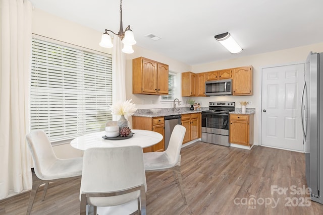 kitchen with an inviting chandelier, appliances with stainless steel finishes, light wood-type flooring, and visible vents