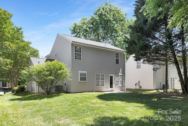 rear view of property featuring a yard, a chimney, central AC unit, and a storage shed