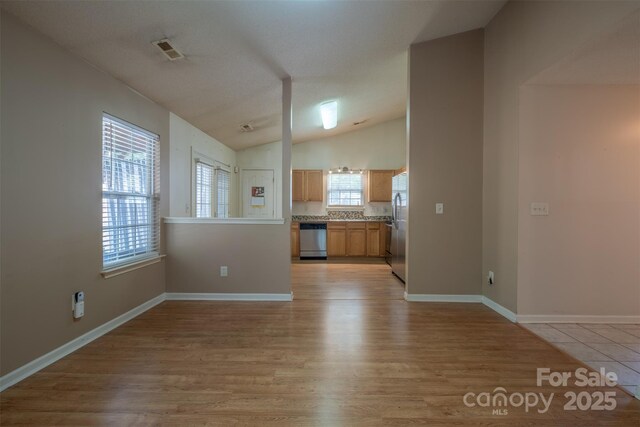 6808 Squirrels Foot Ct, Charlotte, NC 28217 - unfurnished living room with vaulted ceiling, a wealth of natural light, visible vents, and light wood-style floors