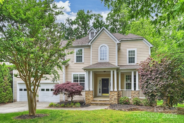 view of front facade with a shingled roof, stone siding, a front yard, covered porch, and driveway