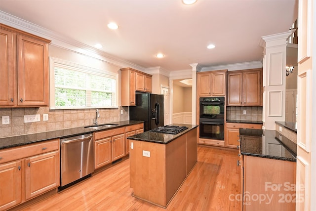 kitchen featuring a kitchen island, dark stone counters, a sink, light wood-style flooring, and black appliances