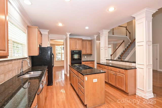 kitchen featuring a sink, a kitchen island, decorative columns, and gas stovetop