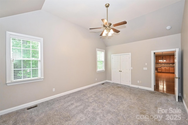 unfurnished bedroom featuring visible vents, vaulted ceiling, baseboards, a closet, and carpet flooring