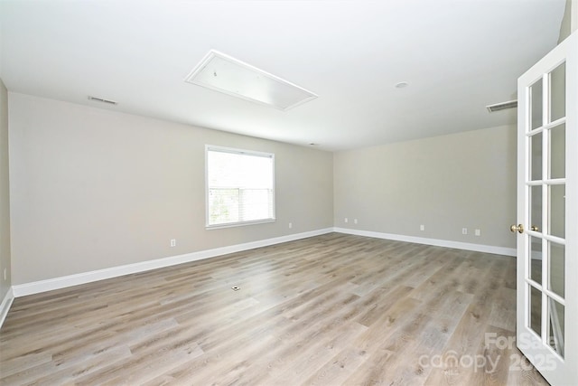 empty room with baseboards, attic access, light wood-style flooring, and visible vents