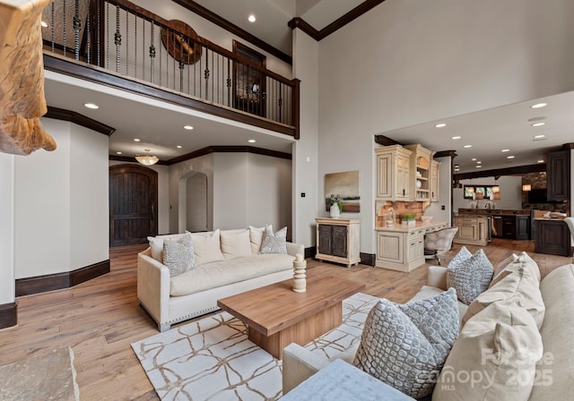 172 Tennessee Cir, Mooresville, NC 28117 - living area featuring ornamental molding, light wood finished floors, a high ceiling, baseboards, and arched walkways