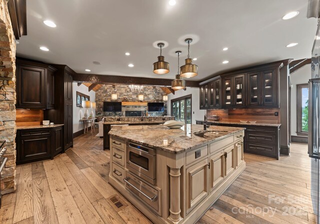 172 Tennessee Cir, Mooresville, NC 28117 - kitchen with a sink, open floor plan, stainless steel microwave, a center island with sink, and light wood finished floors