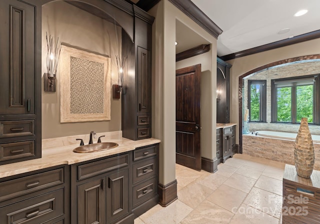 172 Tennessee Cir, Mooresville, NC 28117 - bathroom featuring vanity, a garden tub, stone tile floors, baseboards, and crown molding