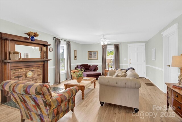 living room featuring light wood-type flooring, a ceiling fan, and a wealth of natural light