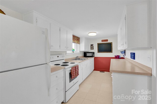 kitchen featuring a sink, light countertops, white cabinets, and white appliances