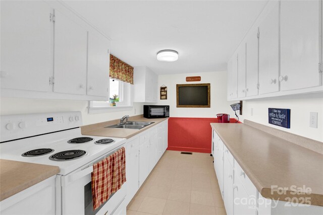 kitchen with a sink, white range with electric stovetop, black microwave, and light countertops